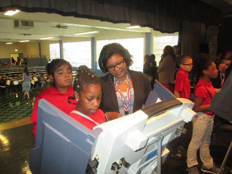 Deborah Upchurch helps students at Knight Road Elementary with using machines as they complete their ballots.